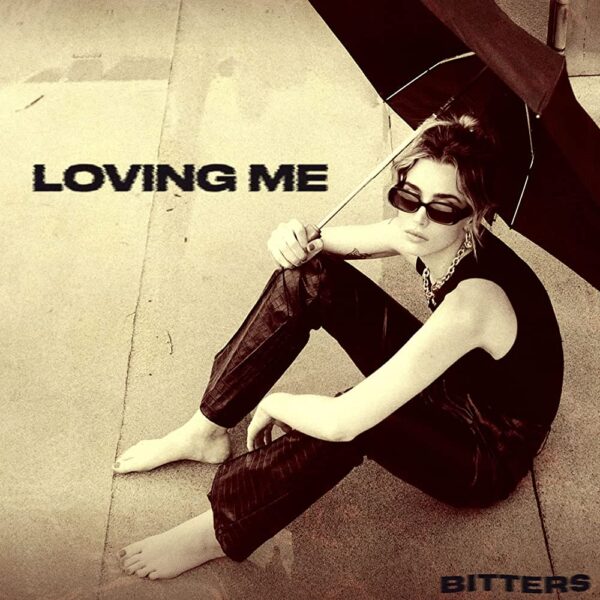 Loving Me cover art. Claudia Mills sat holding an umbrella and looking up at the camera. Pictured in sepia.