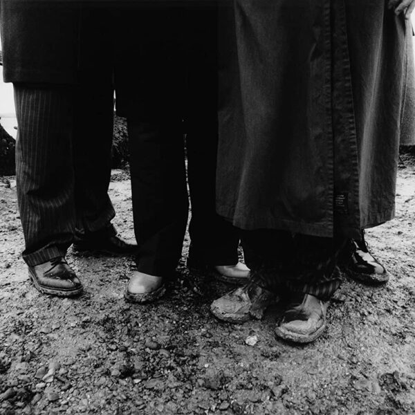 Black and white pictures of men wearing trousers and shoes on the beach. Only their legs are visible.