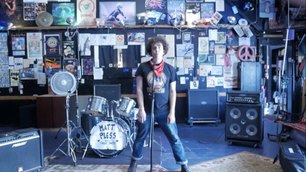 Matt Pless stands in front of a wall covered in ephemera.