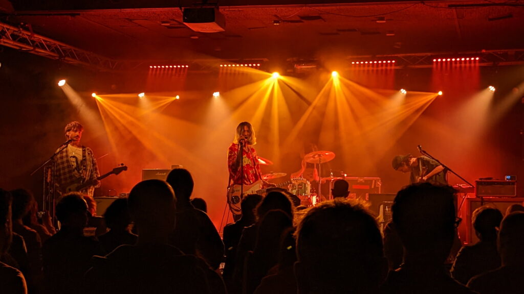 Daisy Brain surrounded by organge light beams on stage at The Wedgewood Rooms