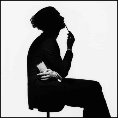 The 1975 - All I Need to Hear. Singer Matty Healy sits silhouetted against a white background.