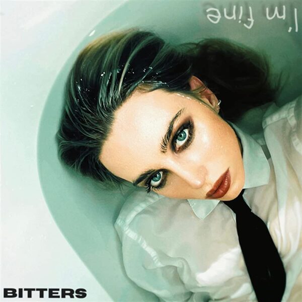 Album cover for Bitters EP I'm Fine. Claudia Mills dressed for business, but laying in a bath.