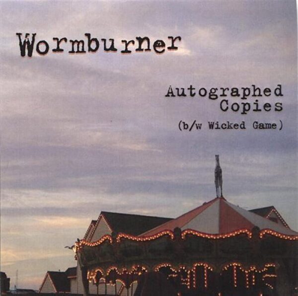 Wormburner - Autographed Copies. An old fairground outlined by warm white lights and a moody sky.