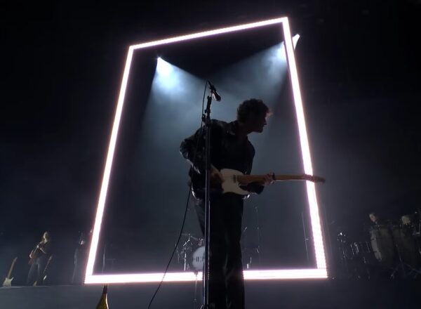The 1975 at Reading Festival. Matty Healey in front of a giant white neon rectangle.